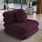 Deep plum velvet armless chair styled on a woven rug near floor-to-ceiling windows with potted greenery