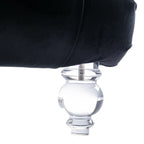 Close-up of the Rochelle Chaise's faceted, crystal-clear acrylic foot beneath black velvet upholstery