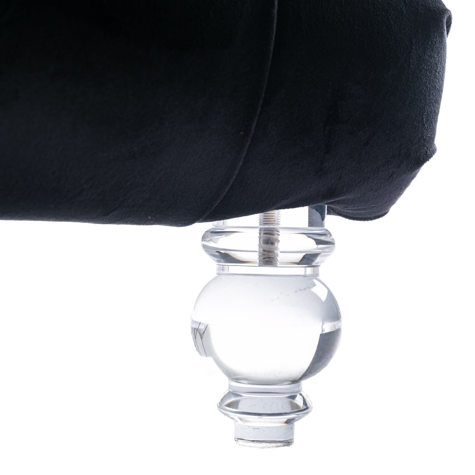 Close-up of the Rochelle Chaise's faceted, crystal-clear acrylic foot beneath black velvet upholstery