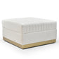 Ivory velvet channel-tufted ottoman with brushed gold plinth base on a white background