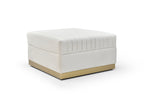 Ivory velvet channel-tufted ottoman with brushed gold plinth base on a white background