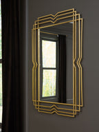 Gold layered-frame mirror hung on a dark charcoal wall beside a curtained window