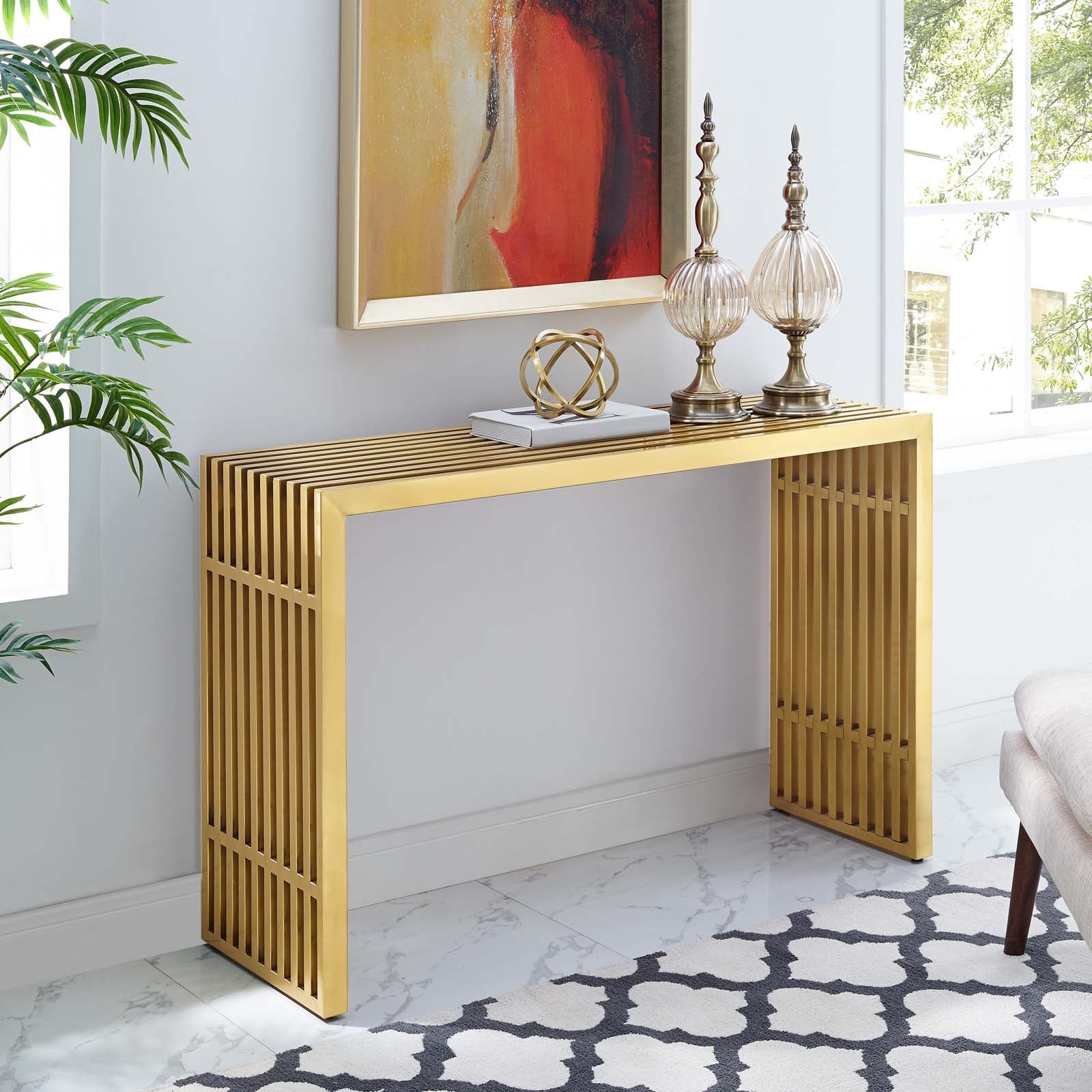 Gold tubular console table styled with brass finials and decorative accents beneath a framed painting