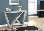 Dark gray console table with asymmetrical wedge base, styled with framed photos and a floral arrangement against a blue wall