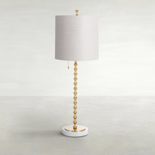 Full view of the Adèle Table Lamp with a cylindrical linen shade, segmented warm-gold stem, and round white marble base.