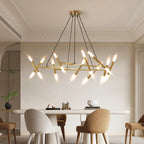 Low-angle editorial dining room presentation of the illuminated Apex Matrix chandelier in matte gold, suspended over a modern white capsule dining table with minimalist chairs.
