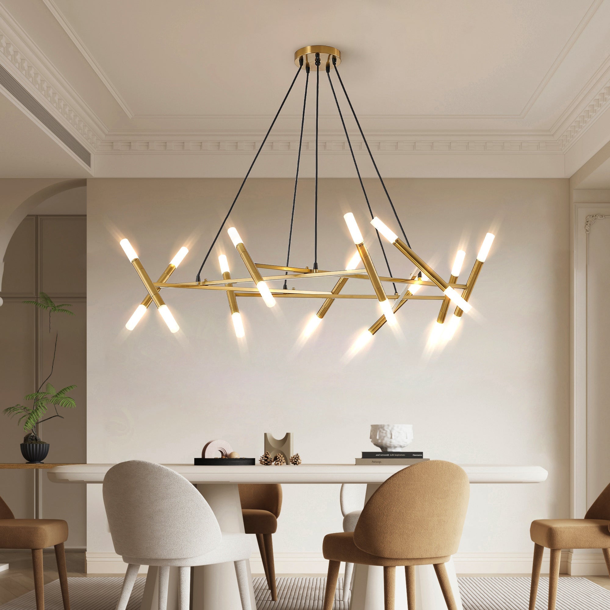 Low-angle editorial dining room presentation of the illuminated Apex Matrix chandelier in matte gold, suspended over a modern white capsule dining table with minimalist chairs.