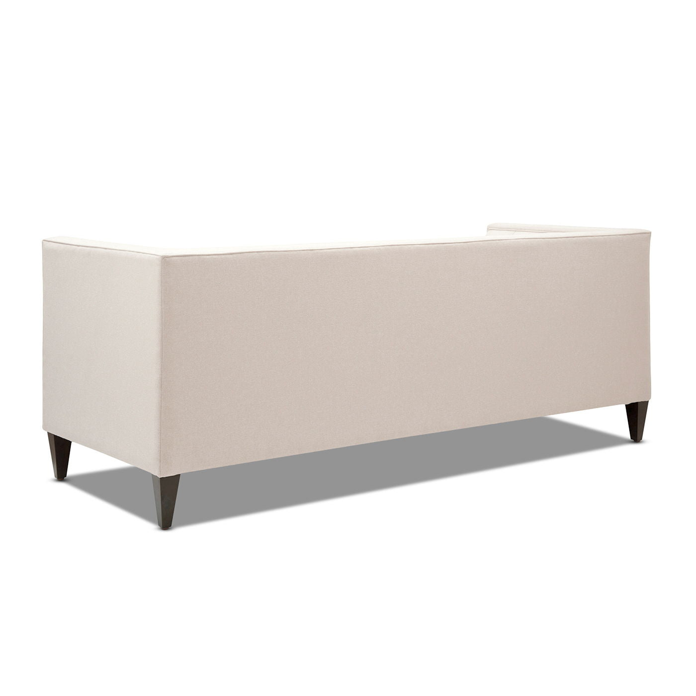Rear three-quarter studio angle of the Cadence tuxedo sofa in a clean, sophisticated neutral beige fabric, demonstrating the completely flat and taut un-tufted back architecture.