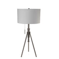 Straight-on studio presentation of the Gaston lamp, showcasing its brushed nickel tripod legs, height-adjustable neck shaft, neutral drum shade, and hanging pull chain against a white backdrop.