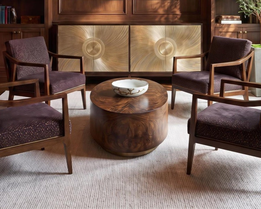 Nadine Bowl styled on a round dark wood coffee table in a warm library seating area with plum upholstered chairs and a sculptural gold cabinet.