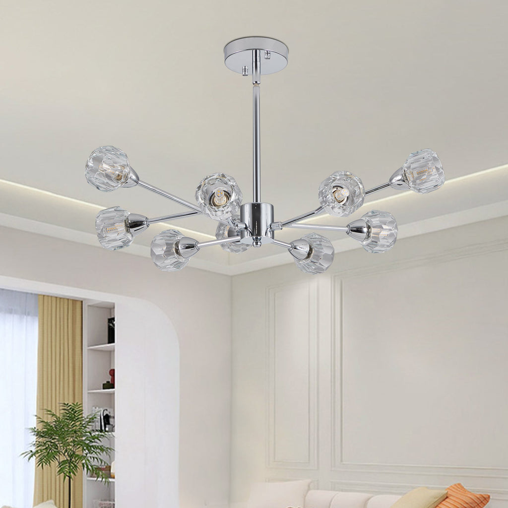 Low-angle lifestyle interior view of the Polaris chrome chandelier illuminating an upscale living space featuring clean architectural wall molding, a neutral cream sofa, and minimalist decor.