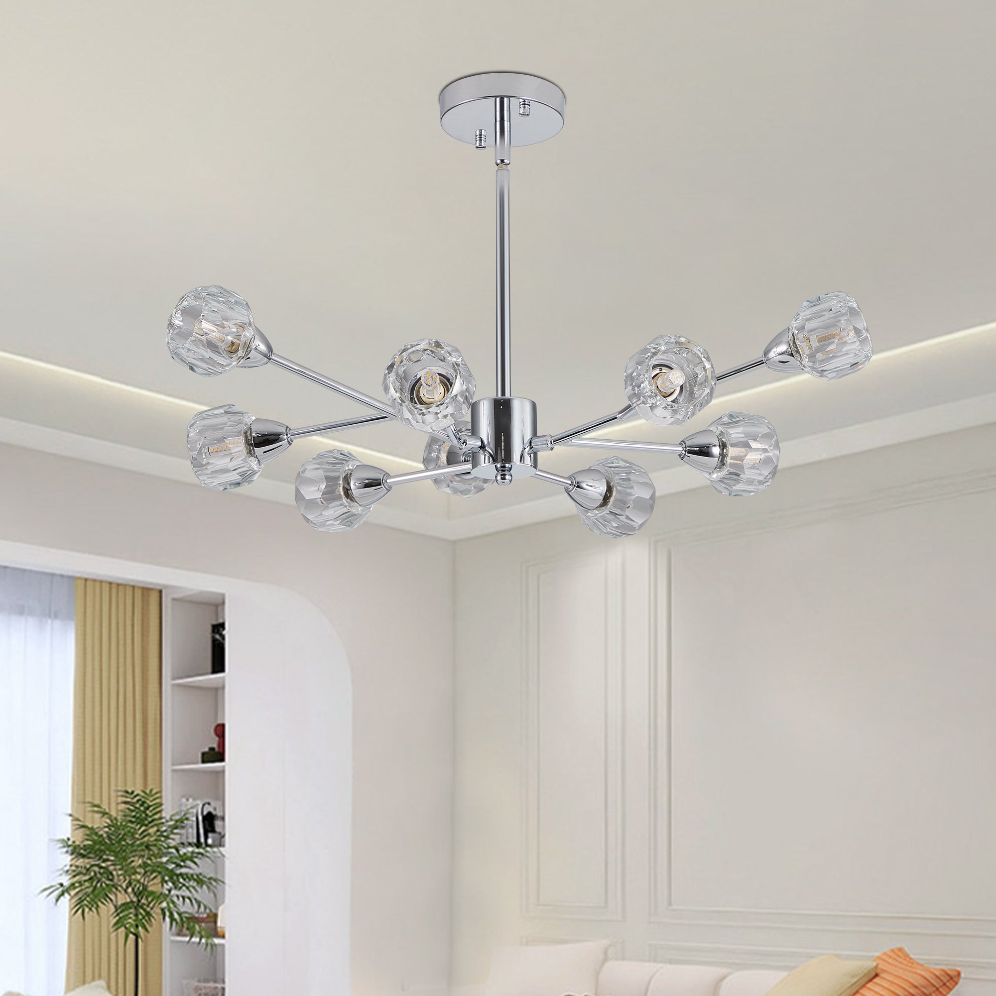Low-angle lifestyle interior view of the Polaris chrome chandelier illuminating an upscale living space featuring clean architectural wall molding, a neutral cream sofa, and minimalist decor.
