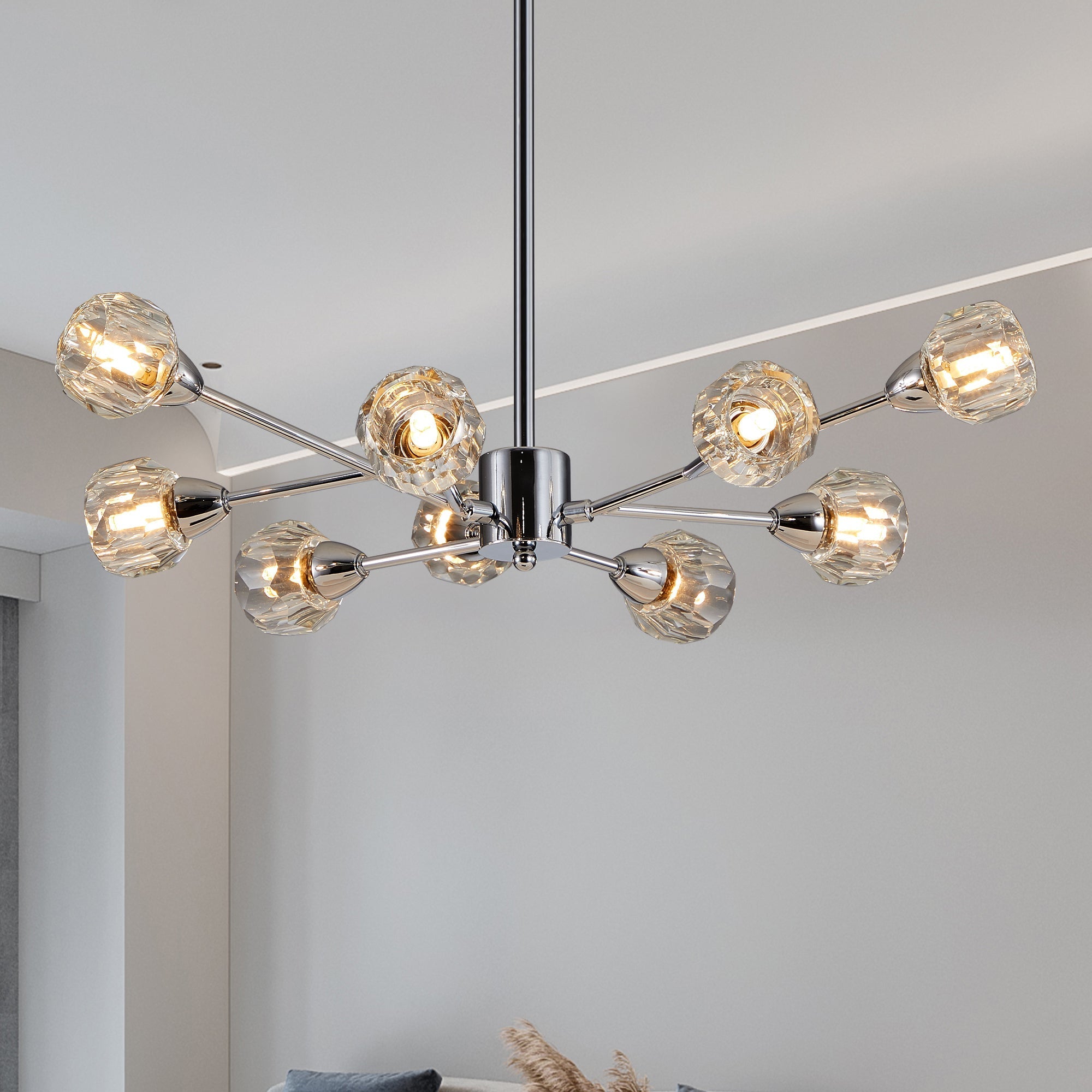 Editorial lifestyle shot of the Polaris 9-light chandelier in polished chrome, showcasing its linear sputnik frame structure and illuminated faceted crystal glass globes.