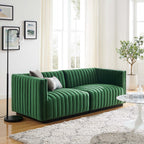 Editorial living room presentation of the Velvet Rogue modular loveseat in emerald green velvet, styled on a plush white shag rug next to a modern black floor lamp and a white tulip coffee table.